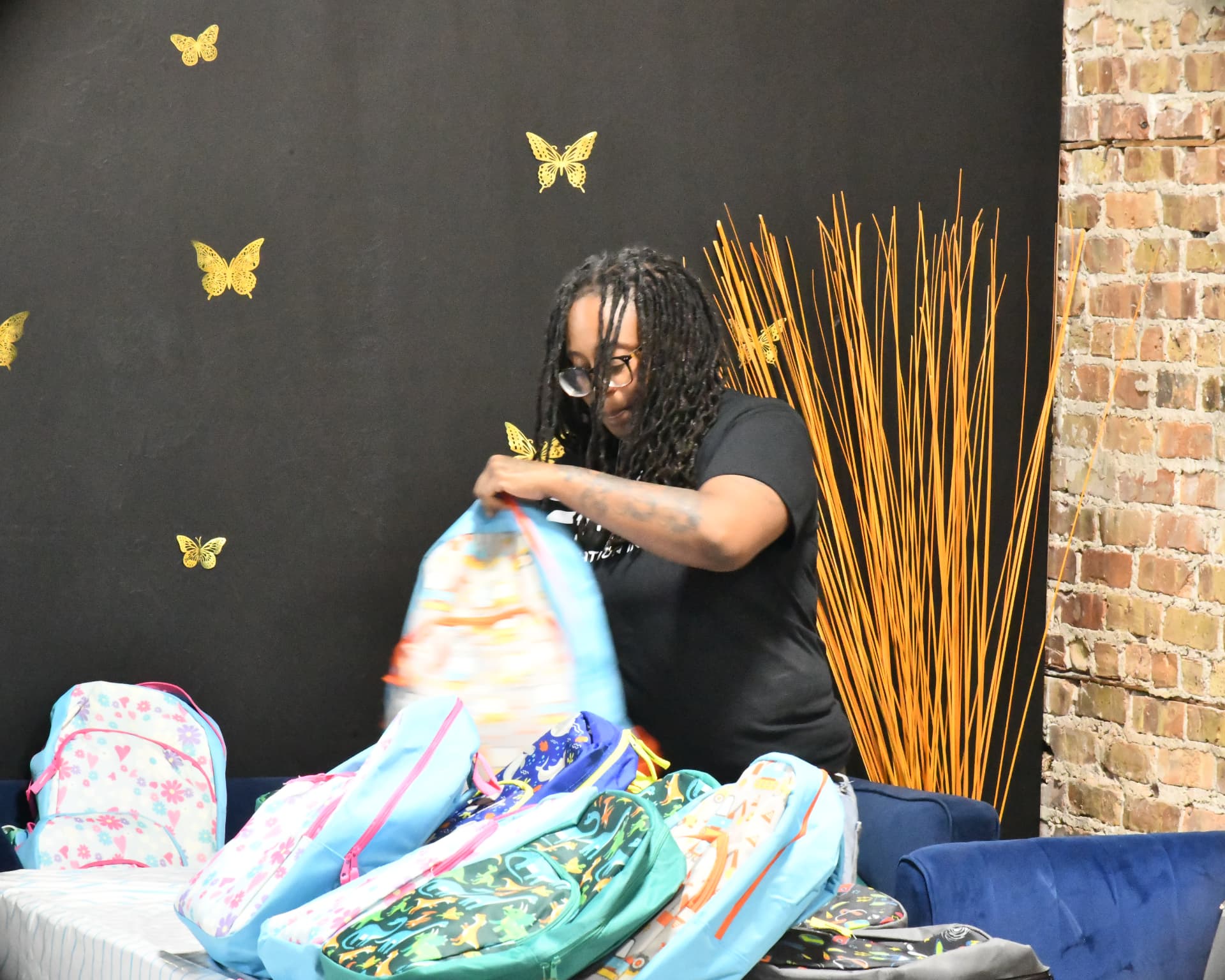 Volunteer packing rows of colorful backpacks with school supplies
