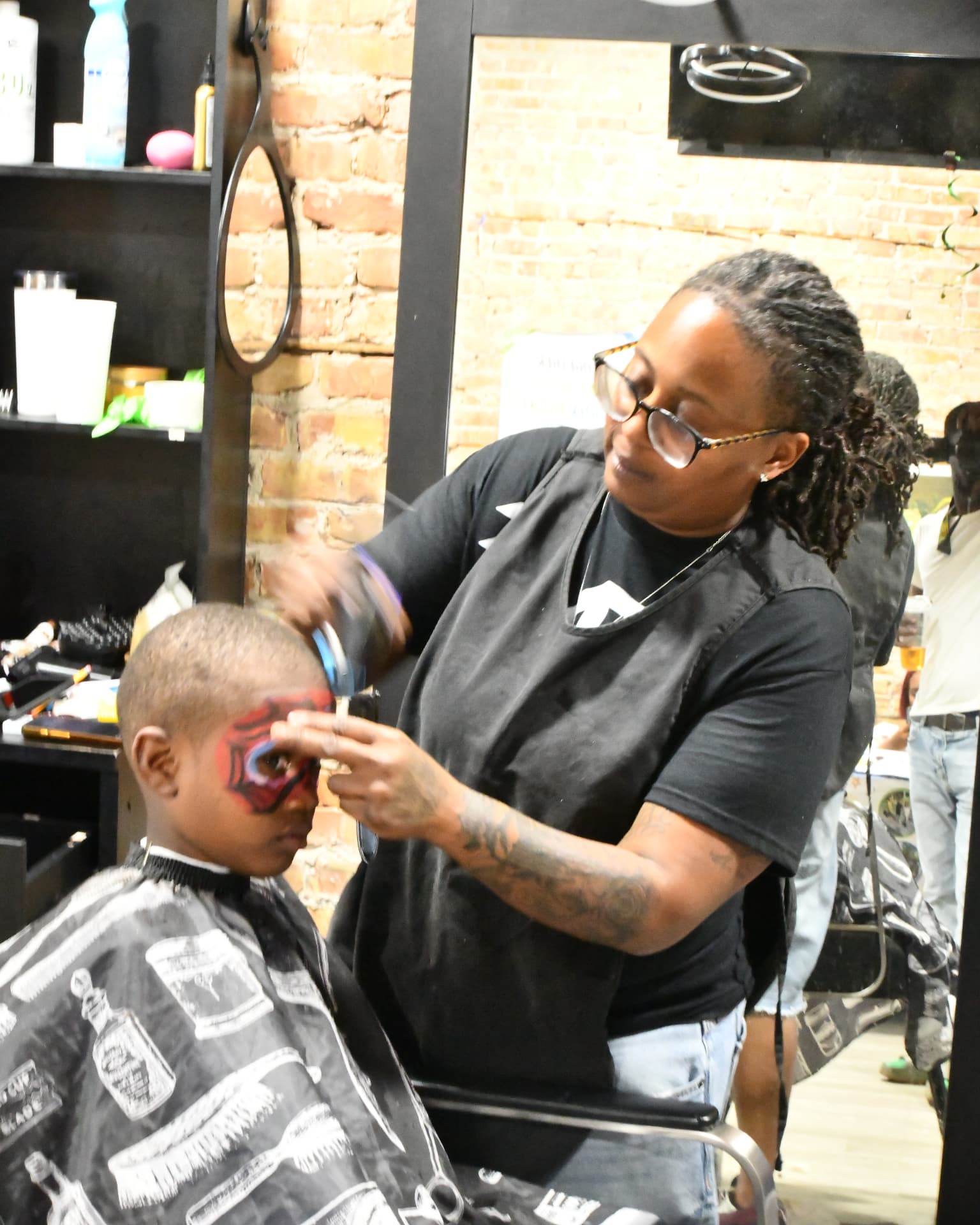 A barber giving a face-painted young boy a free haircut